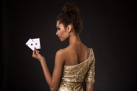 Woman winning - Young woman in a classy gold dress holding two aces, a poker of aces card combination.の写真素材
