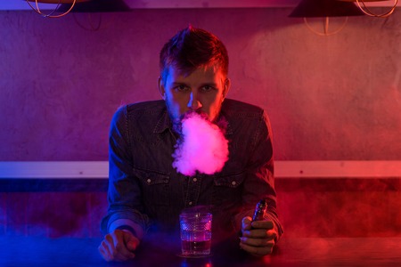 The man smoke an electronic cigarette at the vape shop.