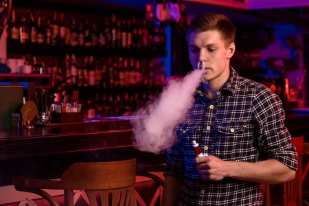 The man smoke an electronic cigarette at the vape shop.の写真素材