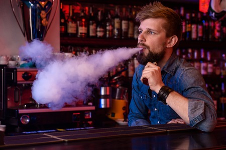 Vape. Vaping man in a cloud of vapor. Photo is taken in a vape bar.の写真素材