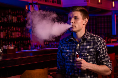 The man smoke an electronic cigarette at the vape shop.の写真素材