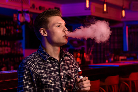 The man smoke an electronic cigarette at the vape shop.の写真素材