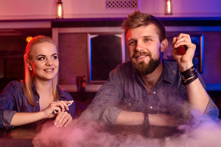 A man and woman smoking electronic cigarette in a vape bar.の写真素材