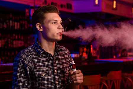 The man smoke an electronic cigarette at the vape shop.の写真素材