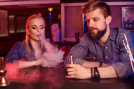 A man and woman smoking electronic cigarette in a vape bar.の写真素材