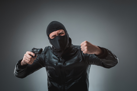 Masked robber with gun, looking into the camera.の写真素材