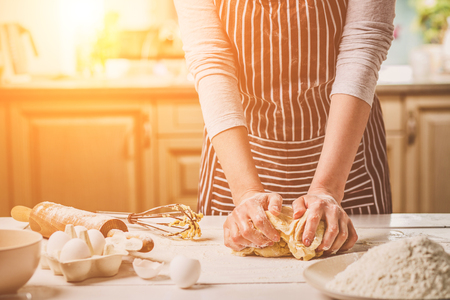 Woman hands kneading dough on kitchen tableの写真素材