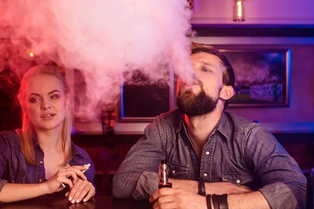 A man and woman smoking electronic cigarette in a vape bar.の写真素材