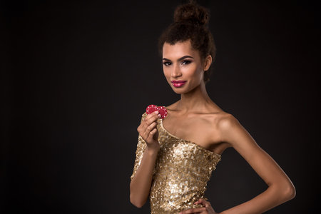 Woman winning - Young woman in a classy gold dress holding two red chips, a poker of aces card combination.の写真素材