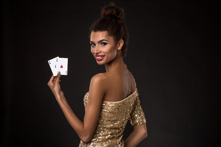 Woman winning - Young woman in a classy gold dress holding two aces, a poker of aces card combination.の写真素材