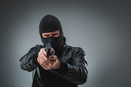 Burglar or terrorist in black mask shooting with gun.の写真素材