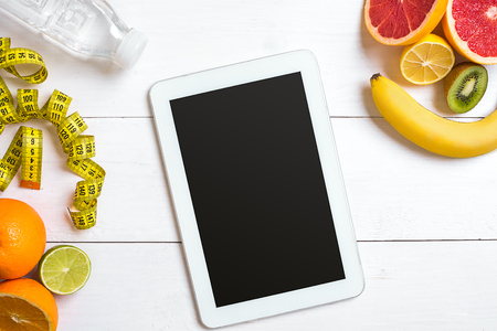 Fresh fruits with tape measure over white wooden background. Top viewの写真素材