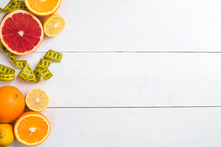 Fresh fruits with tape measure over white wooden background. Top viewの写真素材