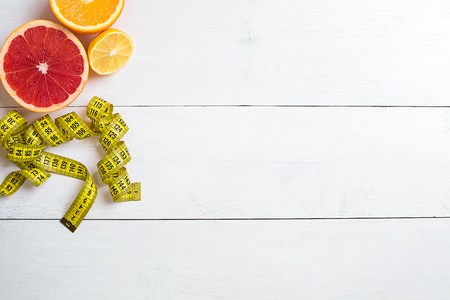 Fresh fruits with tape measure over white wooden background. Top viewの写真素材