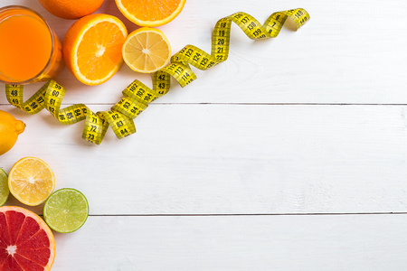 Fresh fruits with tape measure over white wooden background. Top viewの写真素材