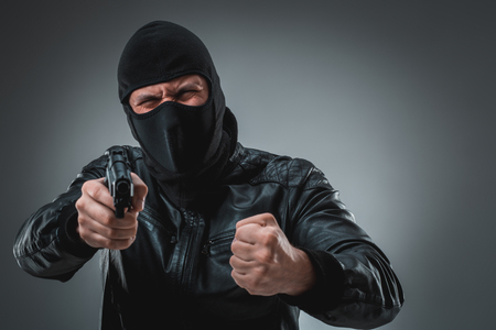 Burglar or terrorist in black mask shooting with gun.の写真素材