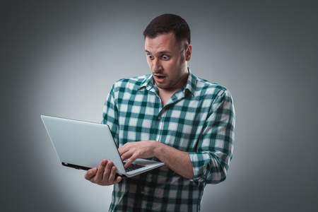 Businessman holding a laptop on gray background.の写真素材
