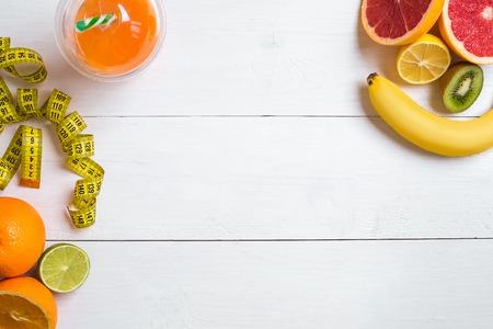 Fresh fruits with tape measure over white wooden background. Top viewの写真素材