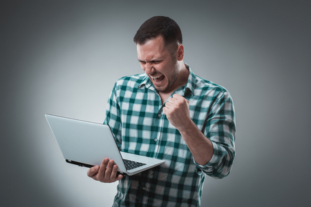 Businessman holding a laptop on gray background.の写真素材