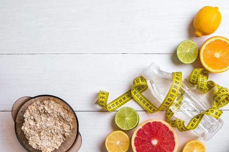 Fresh fruits with tape measure over white wooden background. Top viewの写真素材