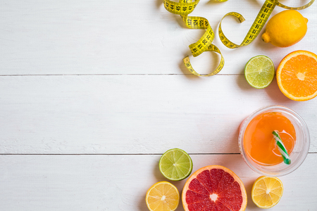 Fresh fruits with tape measure over white wooden background. Top viewの写真素材