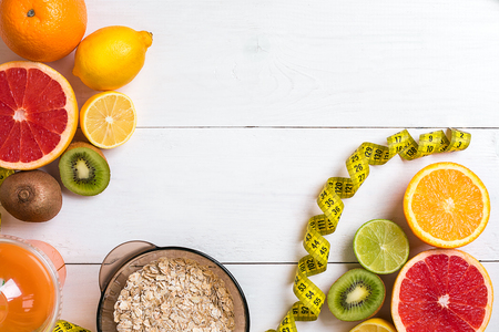 Fresh fruits with tape measure over white wooden background. Fitness concept. Top view. Copy space Flat layの写真素材