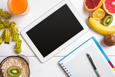 Fresh juice in glass from citrus fruits - lemon, grapefruit, orange, notebook with pencil on white wooden backgroundの写真素材