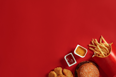 Concept of mock up burger, potatoes, sauce on red background. Copy space for text and logo.の写真素材