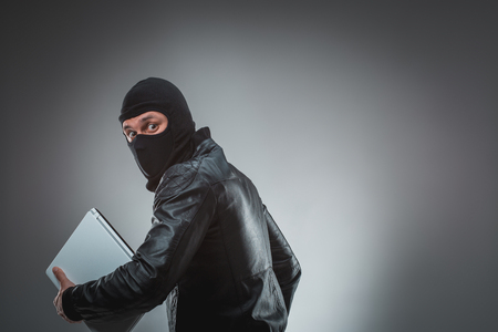 Thief stealing a laptop computer. Isolated on gray backgroundの写真素材
