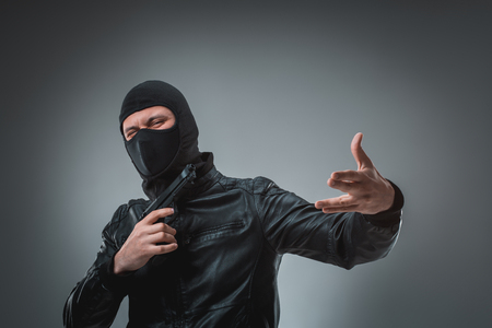 Robber with a gun, studio shotの写真素材