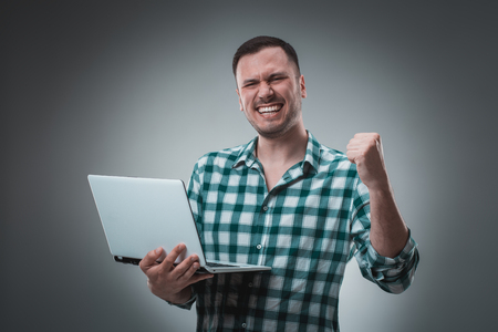 Portrait of young handsome man using laptop, wearing plaid shirtの写真素材