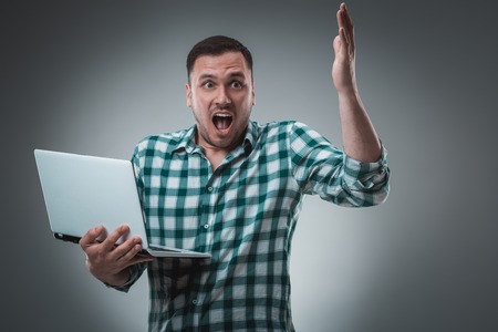 Portrait of young handsome man using laptop, wearing plaid shirtの写真素材