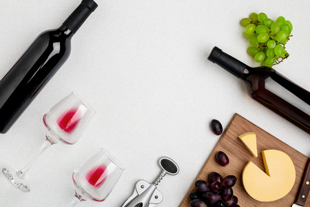 Two wine glasses with red wine,bottle of red wine and cheese on white background.Horizontal view from the top.の写真素材