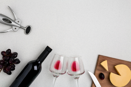 Two wine glasses with red wine,bottle of red wine and cheese on white background.Horizontal view from the top.の写真素材