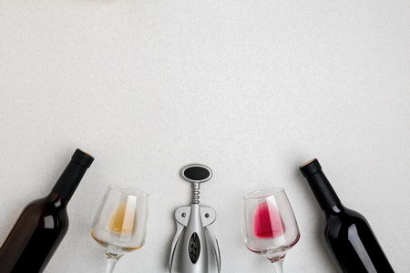 Two wine glasses with red and white wine, bottles of red wine and white wine, corkscrew on white background. Horizontal view from the top.の写真素材