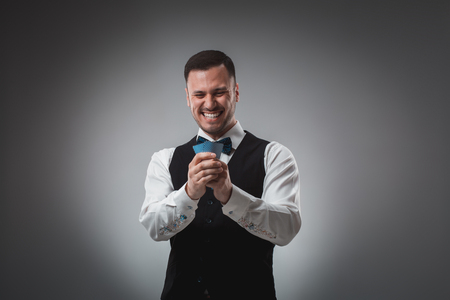 Young man in shirt and waistcoat watch his poker cards, studio shotの写真素材