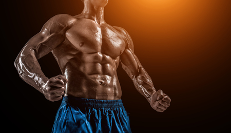 Muscular and fit young bodybuilder fitness male model posing over black background. Studio shot on black background. with sun flare. close-upの写真素材