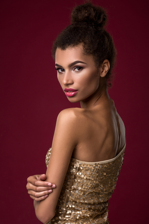 Fashion young African woman with make-up, in sexy gold dress.の写真素材