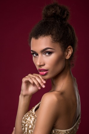 Fashion young African woman with make-up, in sexy gold dress.の写真素材