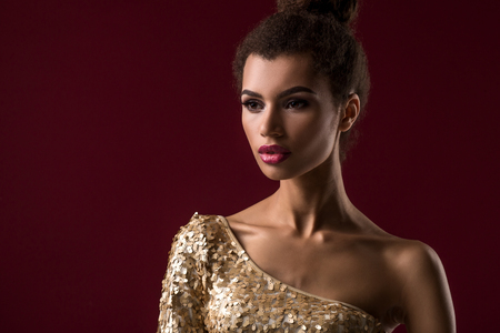 Fashion young African woman with make-up, in sexy gold dress.の写真素材