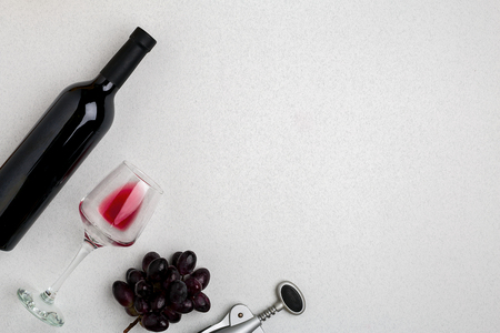 Overhead angled view of a large bottle of red wine, drinking glass on white backgroundの写真素材
