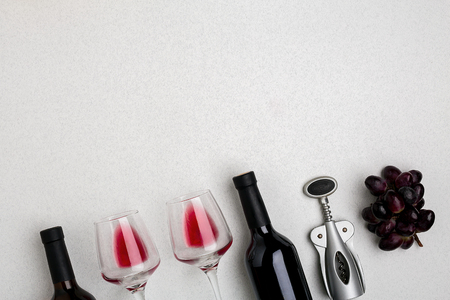 Glasses and bottles of red and white wine on white background from top viewの写真素材