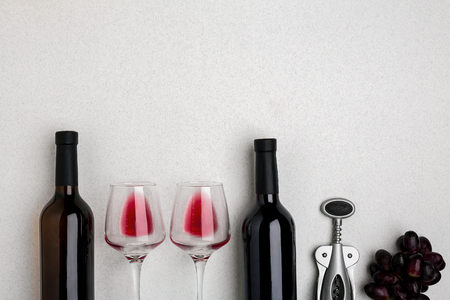 Glasses and bottles of red and white wine on white background from top viewの写真素材