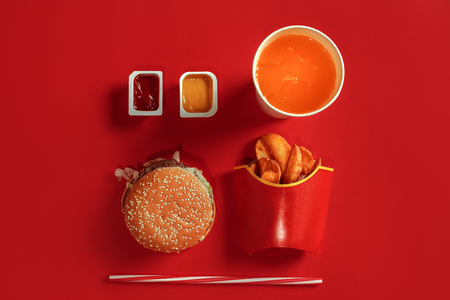 Burger and Chips. Hamburger and french fries in red paper box. Fast food on red background.の写真素材