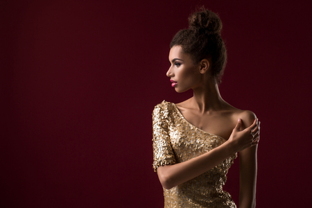 Fashion young African woman with make-up, in sexy gold dress.の写真素材