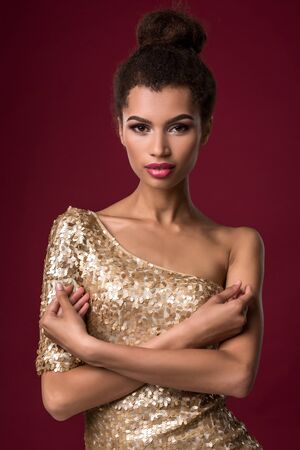 Fashion young African woman with make-up, in sexy gold dress.の写真素材