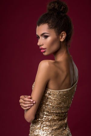 Fashion young African woman with make-up, in sexy gold dress.の写真素材