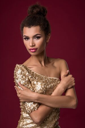 Fashion young African woman with make-up, in sexy gold dress.の写真素材