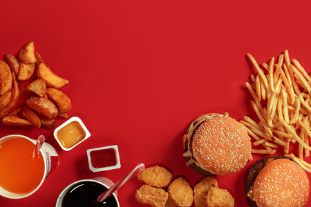 Fast food dish top view. Meat burger, potato chips and glass of drink on red background. Takeaway composition.の写真素材