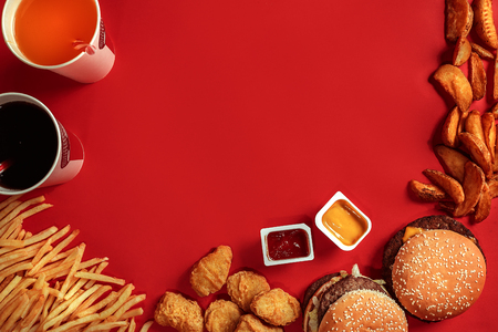 Fast food dish top view. Meat burger, potato chips and glass of drink on red background. Takeaway composition.の写真素材